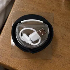 Priyanka S.'s photo: the band and its Type-C charging cable in their packaging, on a bedside table.