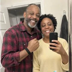 Denise and Curtis smiling in their bathroom mirror, the band on his wrist.